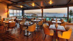 A restaurant with tables and chairs, large windows, and a view of the city and water. - Azade Premier (Istanbul)