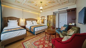A hotel room with two beds, a red armchair, a small table, and a television. - Azade Premier (Istanbul)