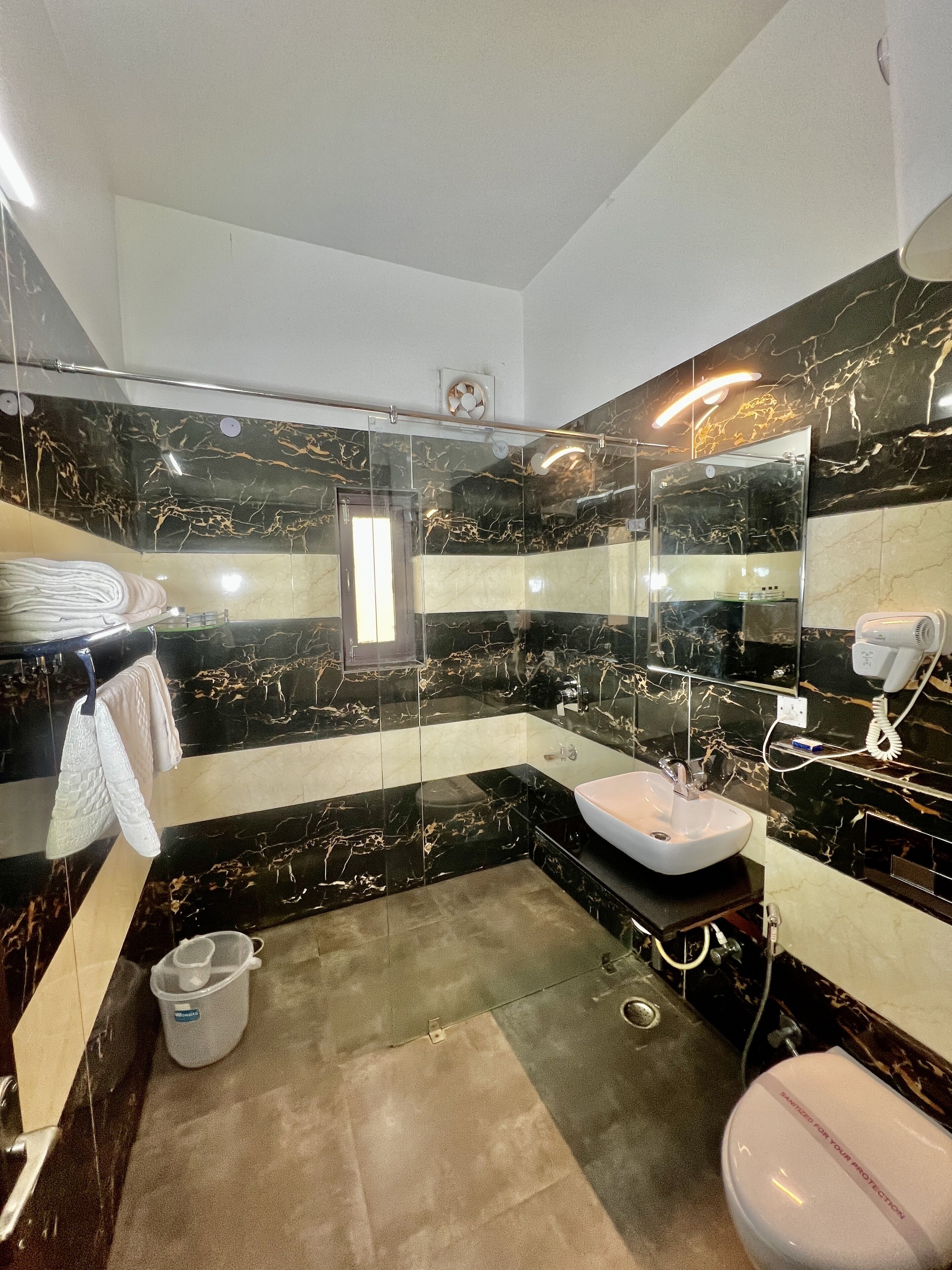 A modern bathroom with a glass shower enclosure, a white sink, and a toilet.