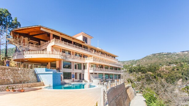 A multi-story building with a pool, balconies, and a view of the surrounding landscape. - Sea Hawk Hill Resort - A Luxury Boutique Resort (Nainital)