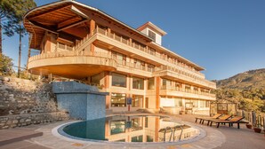 A multi-story building with a pool, balconies, and a stone wall. - Sea Hawk Hill Resort - A Luxury Boutique Resort (Nainital)