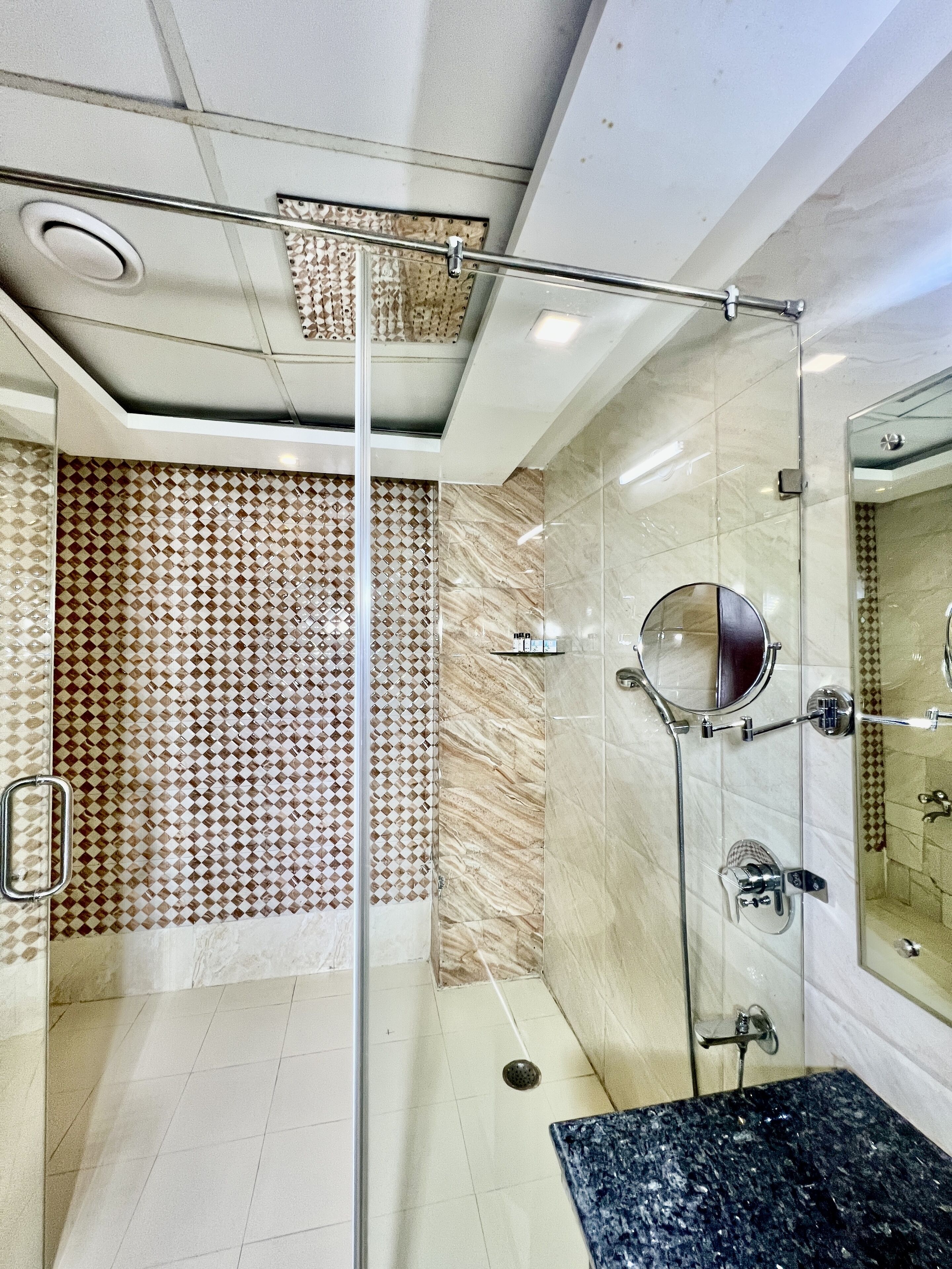 A modern bathroom with a glass shower enclosure, a marble-tiled wall, and a sink with a granite countertop.