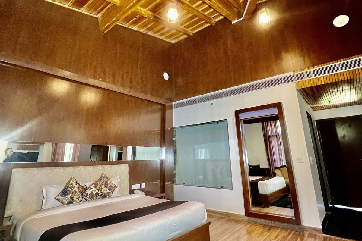 Un dormitorio con techo de madera, cama con alfombra negra y un espejo grande.
