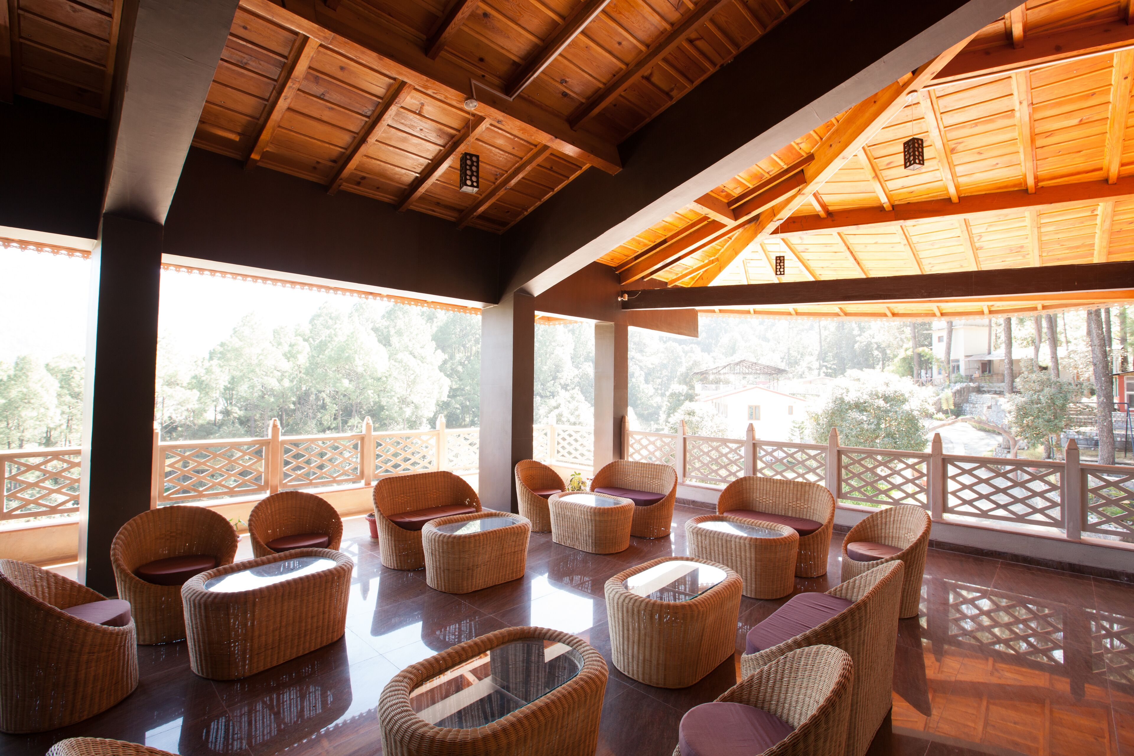 A covered outdoor seating area with wicker furniture and large windows.