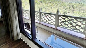 A room with a large window overlooking a mountainous landscape. - Sea Hawk Hill Resort - A Luxury Boutique Resort (Nainital)