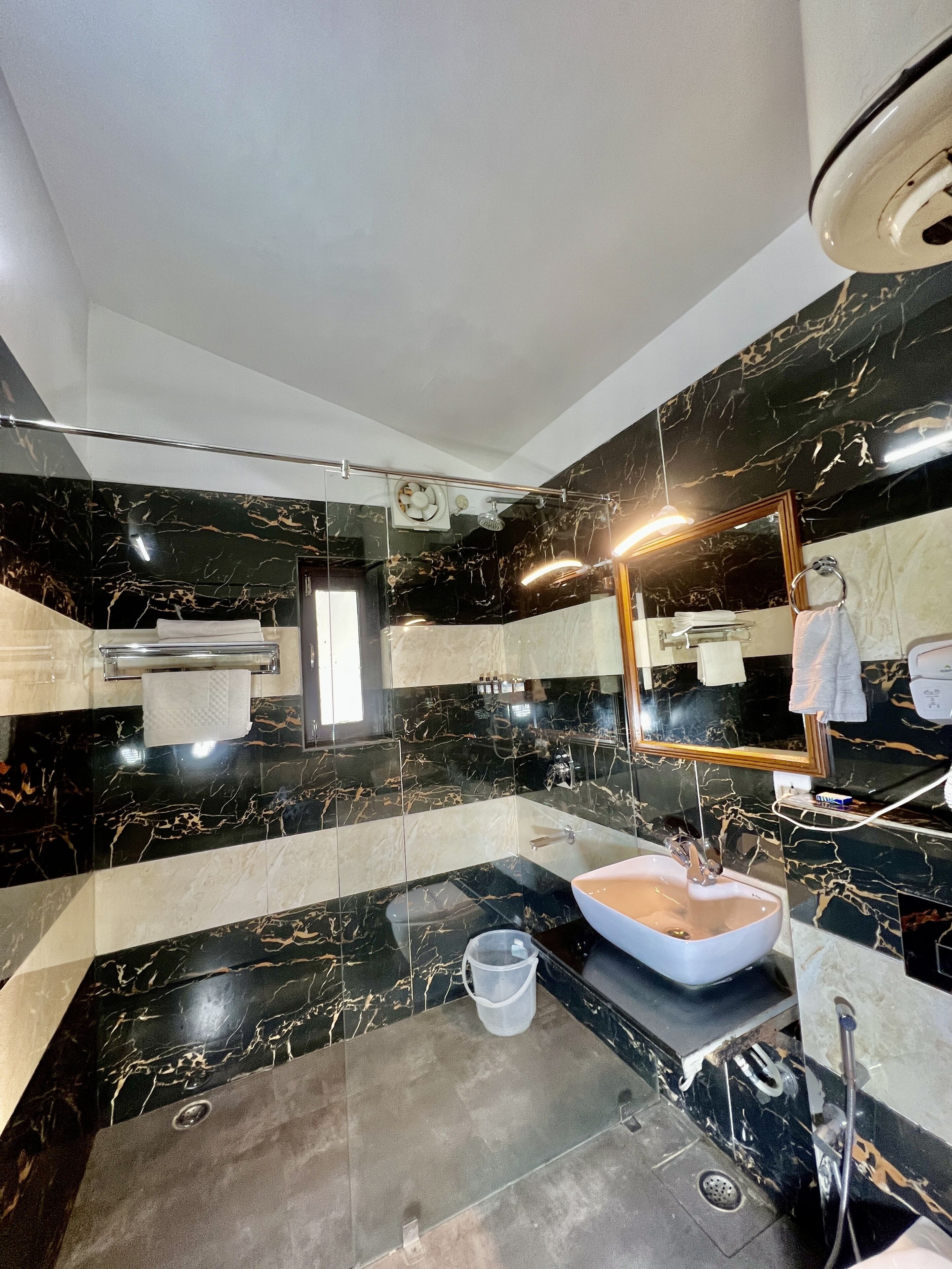 A bathroom with a black and white marble design, a sink, a mirror, and a towel rack.
