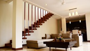 A modern living room with a staircase, a sofa, a coffee table, and pendant lighting.