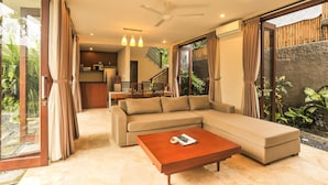 A modern living room with a sectional sofa, a coffee table, and a dining area in the background.