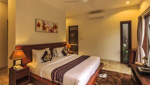 A hotel room with a large bed, a ceiling fan, a nightstand with a lamp, and a window with curtains.