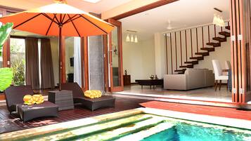 A modern outdoor living area with a pool, lounge chairs, and a staircase leading to an upper level.