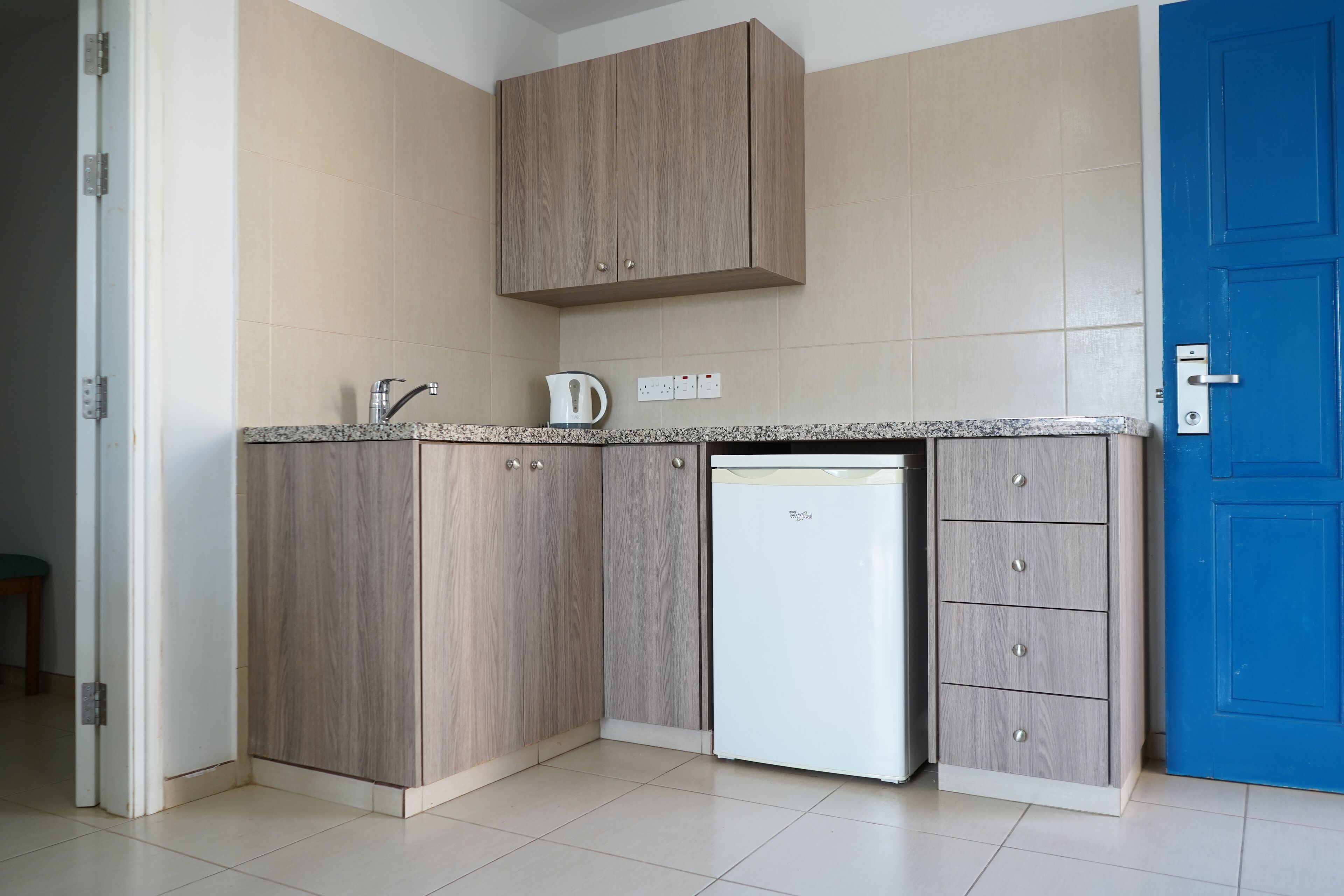 Una cocina compacta con lavavajillas, cafetera y una puerta azul.