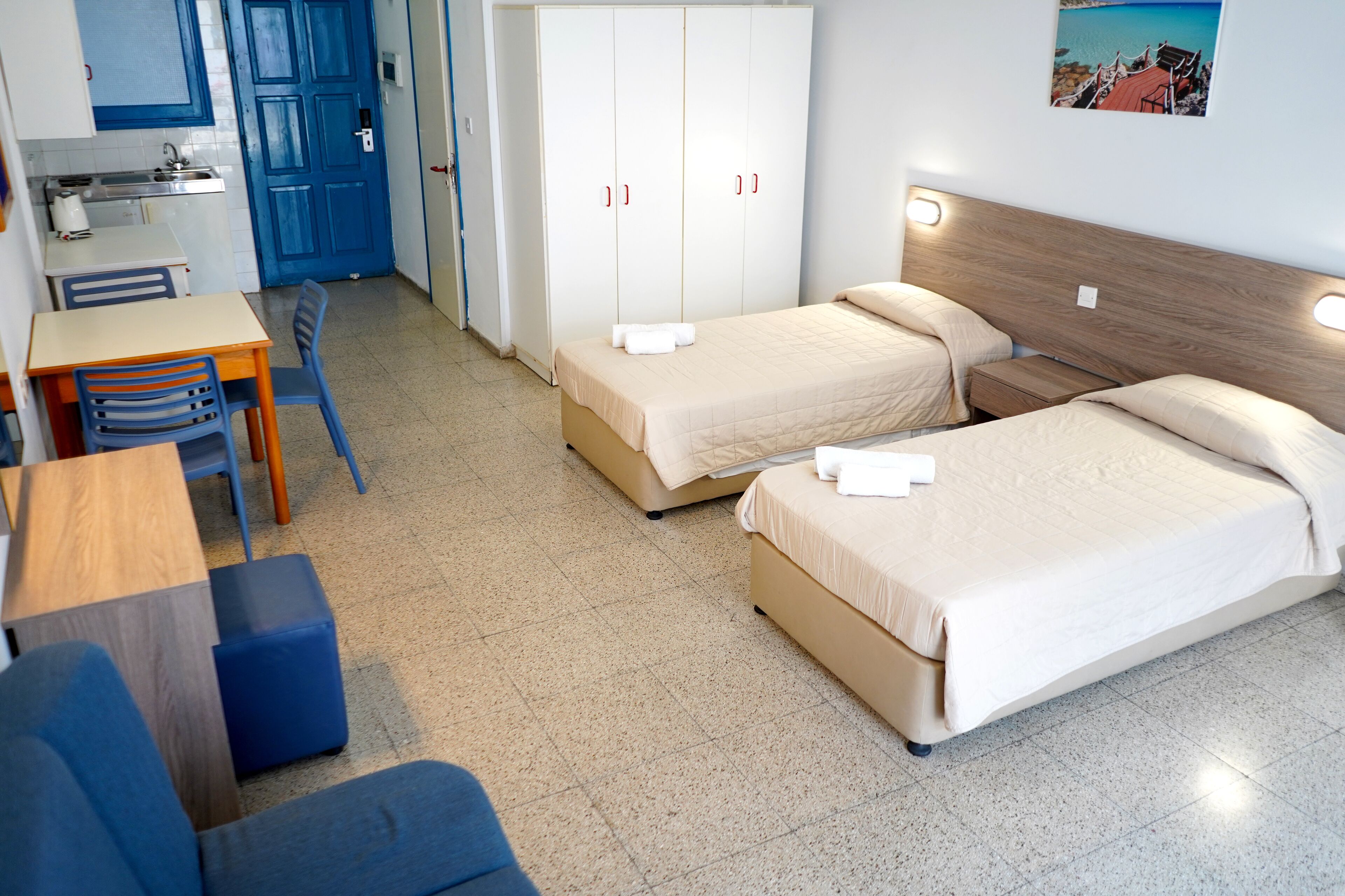Ein Hotelzimmer mit zwei Betten, einer Küchenzeile, einem Essbereich und einem Badezimmer.