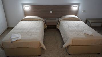 Habitación doble con dos camas, una mesita de noche y una pequeña mesa.