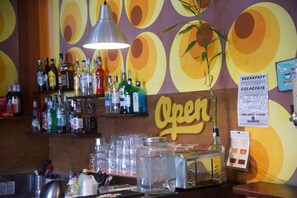 Un espace bar avec un assortiment de bouteilles d’alcool, de verres et un tableau affichant le menu.