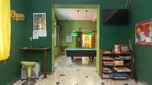 A room with a pool table, a television, and a bookshelf with various items.