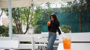 A person sitting at an outdoor table with a drink.