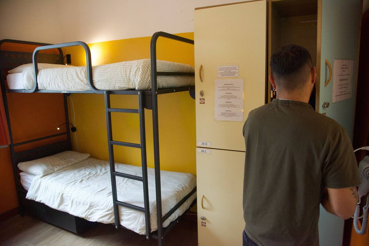 Habitación con literas, un refrigerador y una puerta con un cartel.