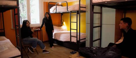 Un dormitorio con literas, una mesa de madera y una ventana con cortinas.