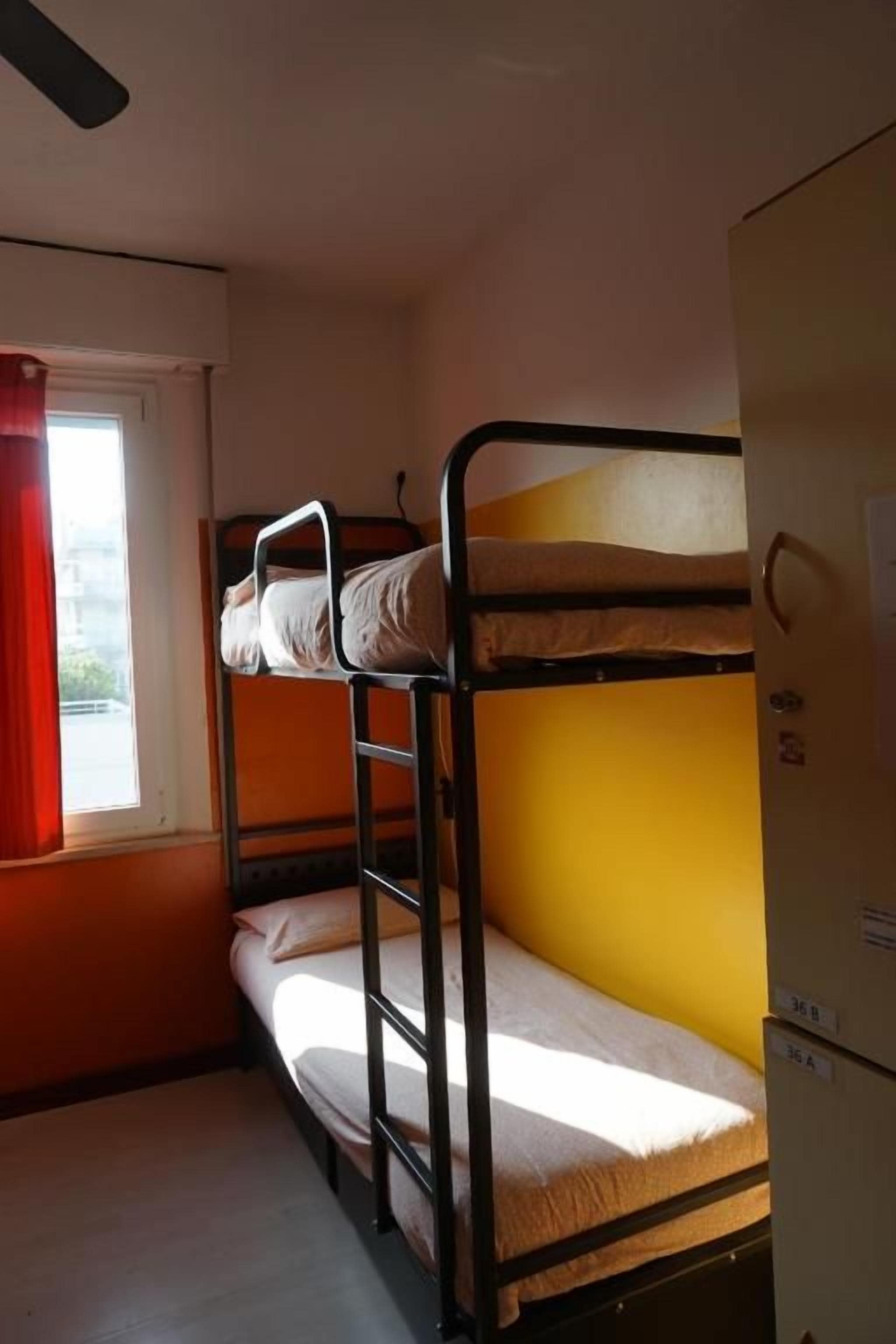 Quarto com beliche, janela, porta e geladeira.