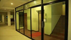A hallway with glass doors leading to a room, a red mat at the entrance, and a staircase to the right. - Tikky Place (Chiang Mai)
