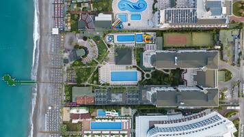 Vista aérea de un hotel costero con varias piscinas, una playa y un puerto deportivo.