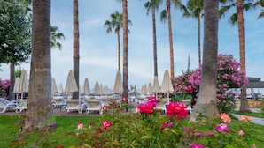 A resort with palm trees, lounge chairs, and pink flowers. - Meryan Hotel - All Inclusive (Alanya)