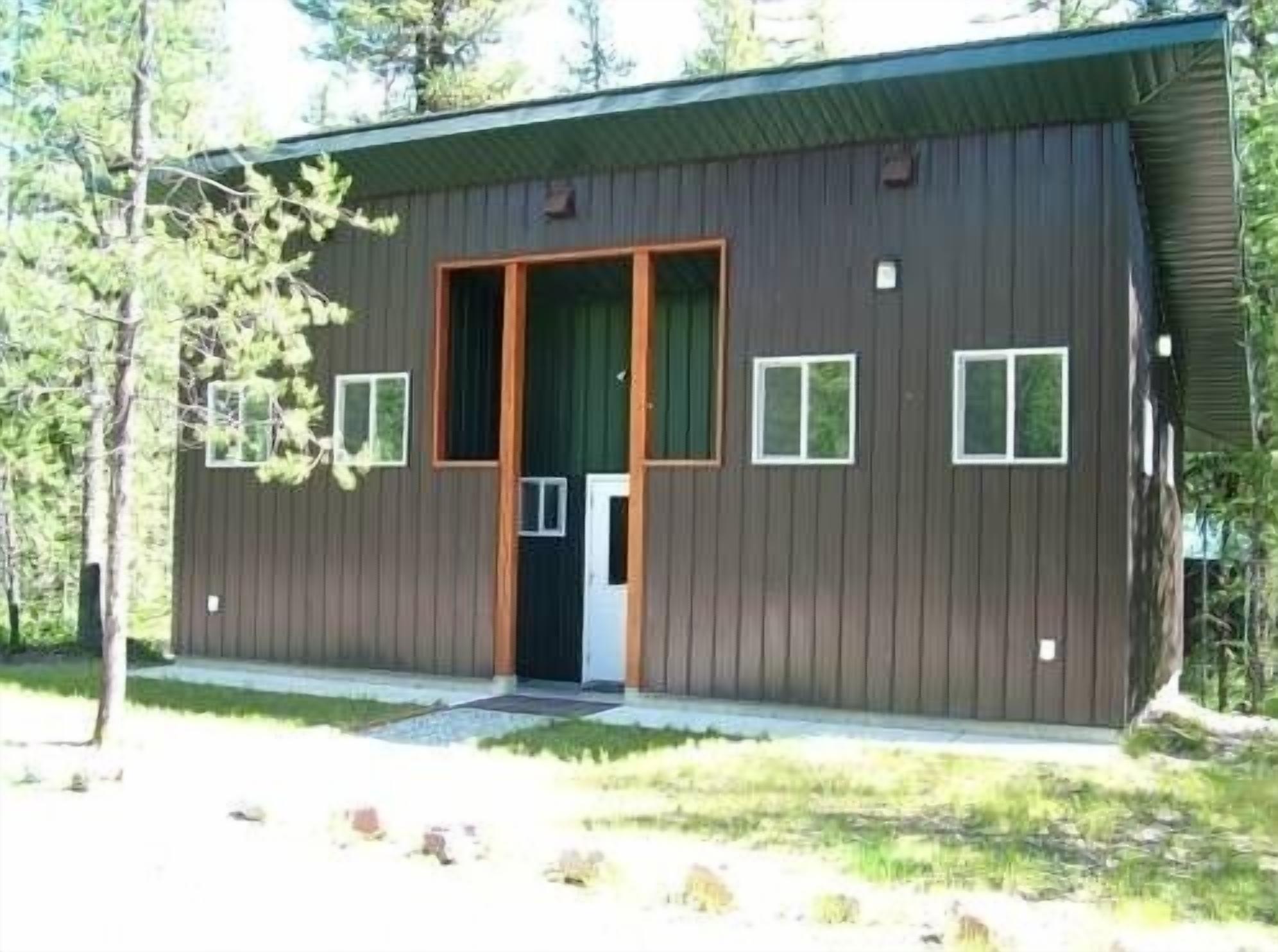 A modern, single-story building with a dark wooden exterior, a central door, and small windows.