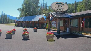A Glacier Haven Inn with a rustic exterior, a signboard, and potted plants with red flowers. - Glacier Haven Inn (Essex)