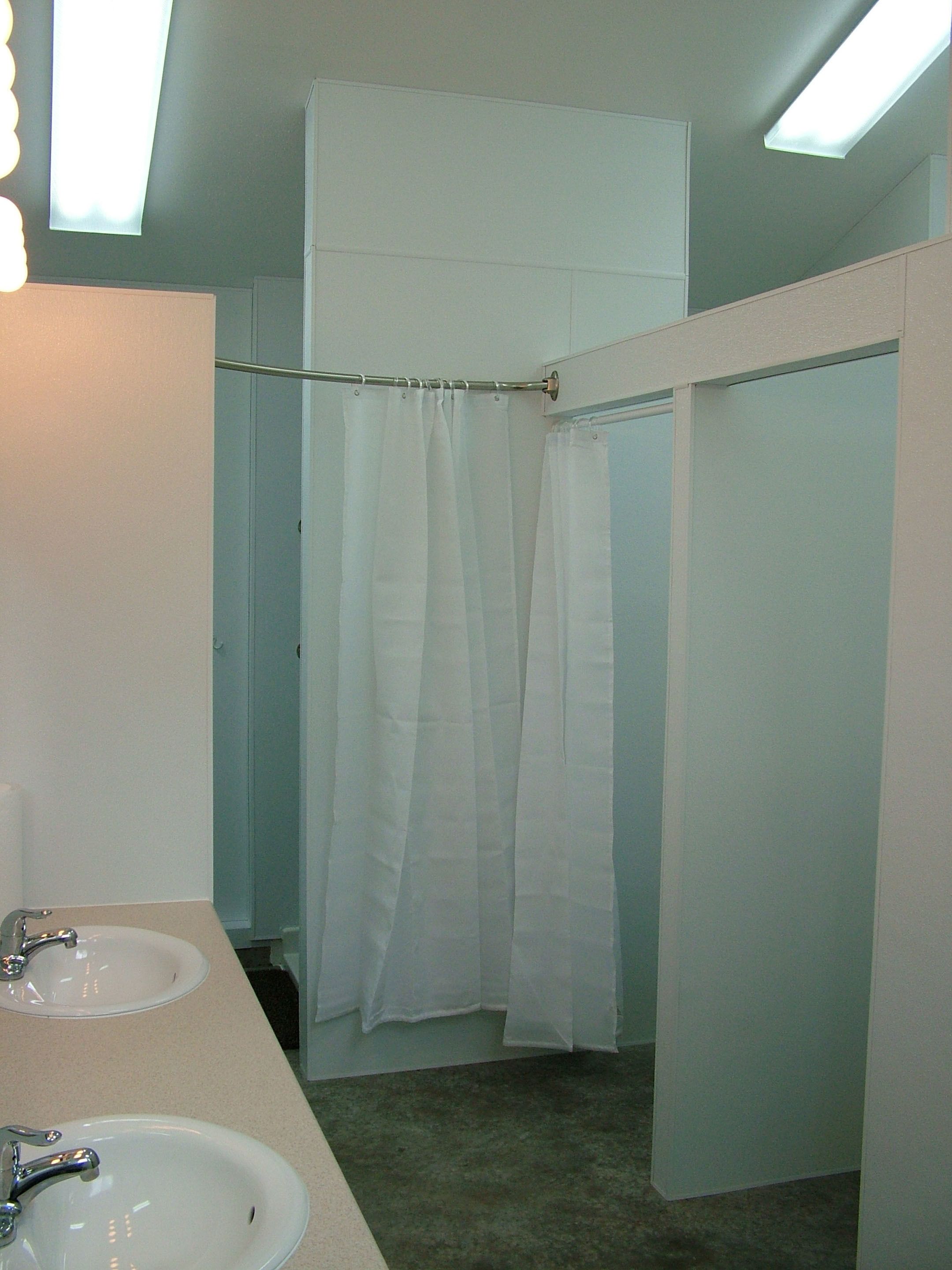 Un bagno con due lavandini, una tenda doccia e un portascopevoli.