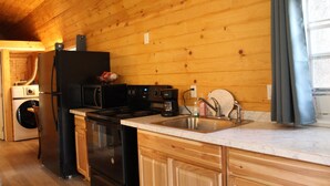 A kitchen with wooden walls, a sink, a stove, and a refrigerator. - Glacier Haven Inn (Essex)