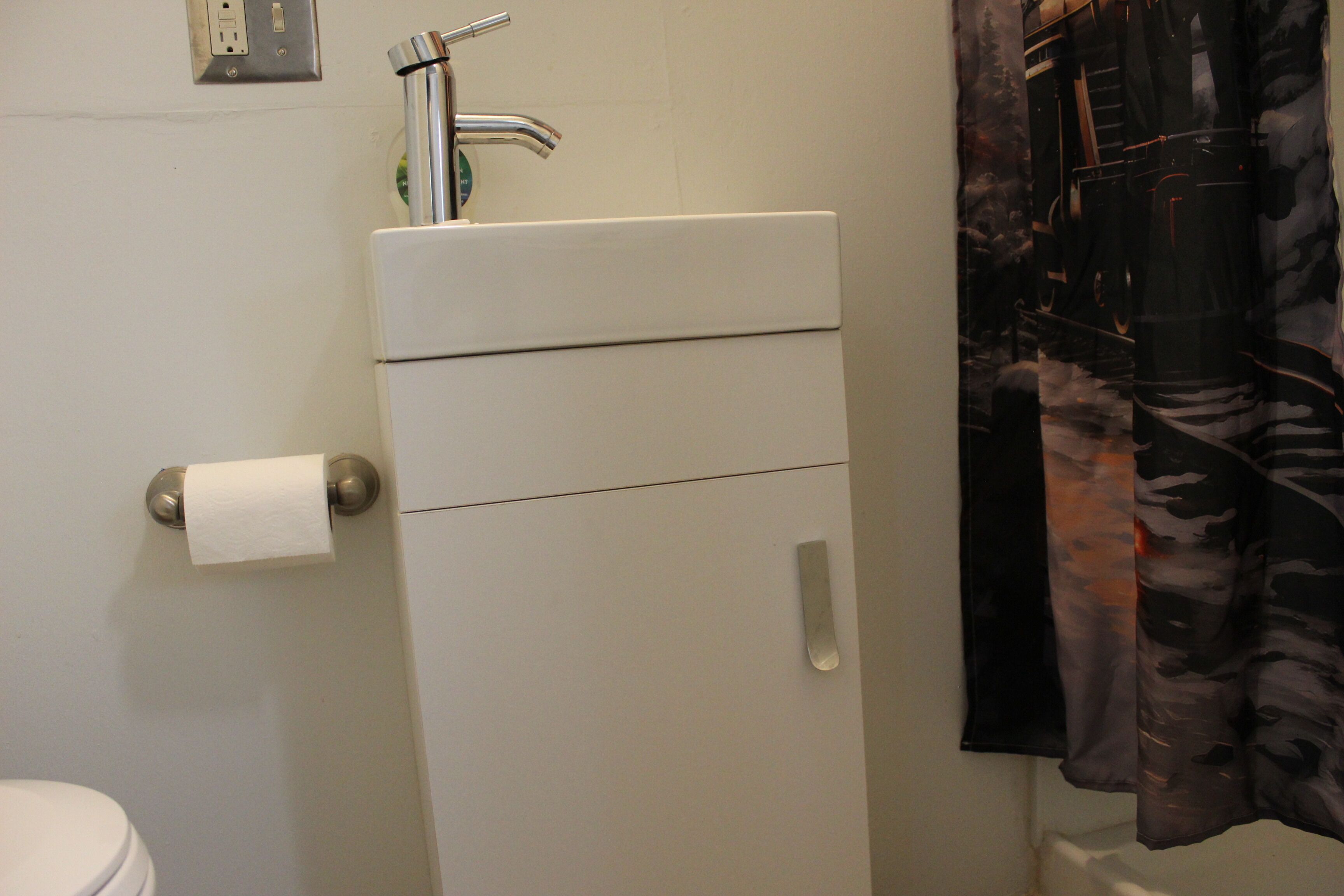 A bathroom with a toilet, sink, and shower curtain.