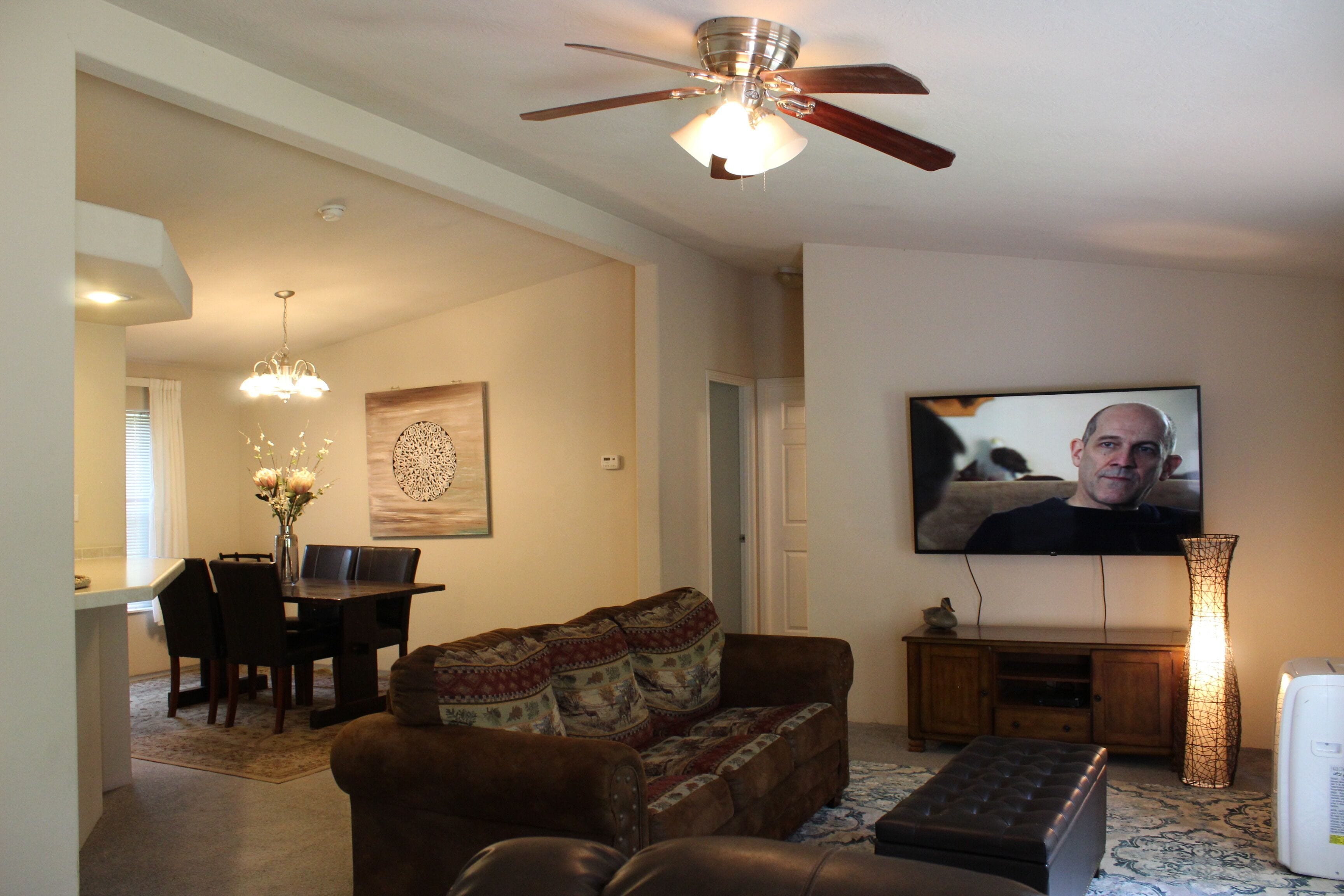 A living room with a sofa, a coffee table, a TV, and a ceiling fan.