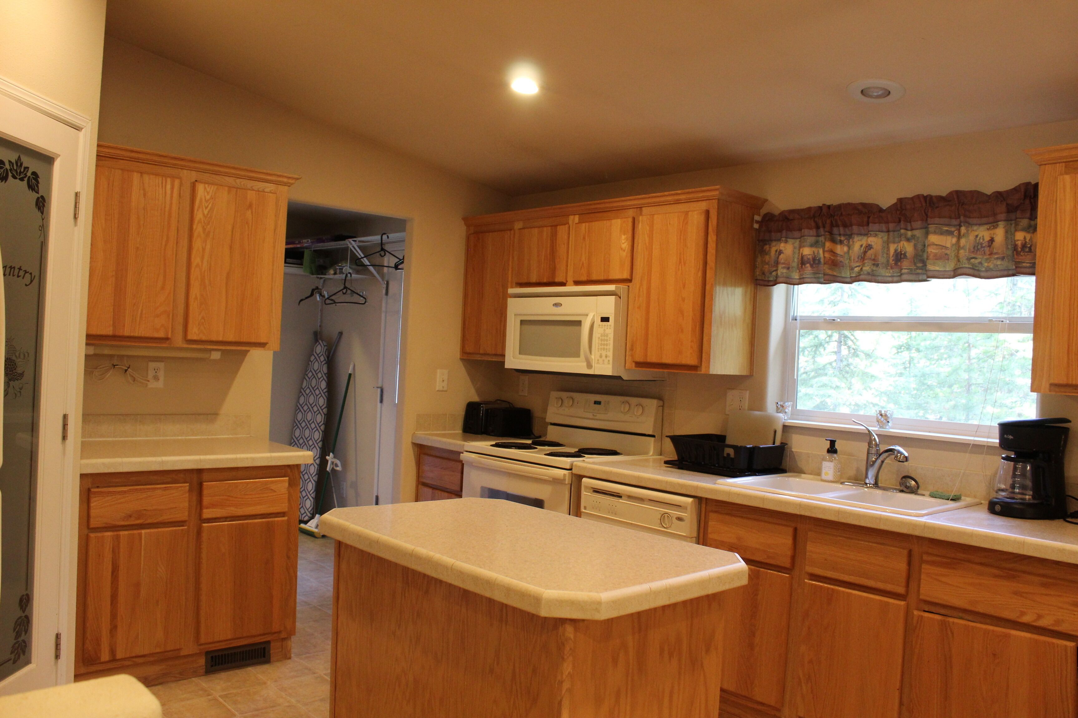 A kitchen with wooden cabinets, a microwave, stove, and a window with a view.