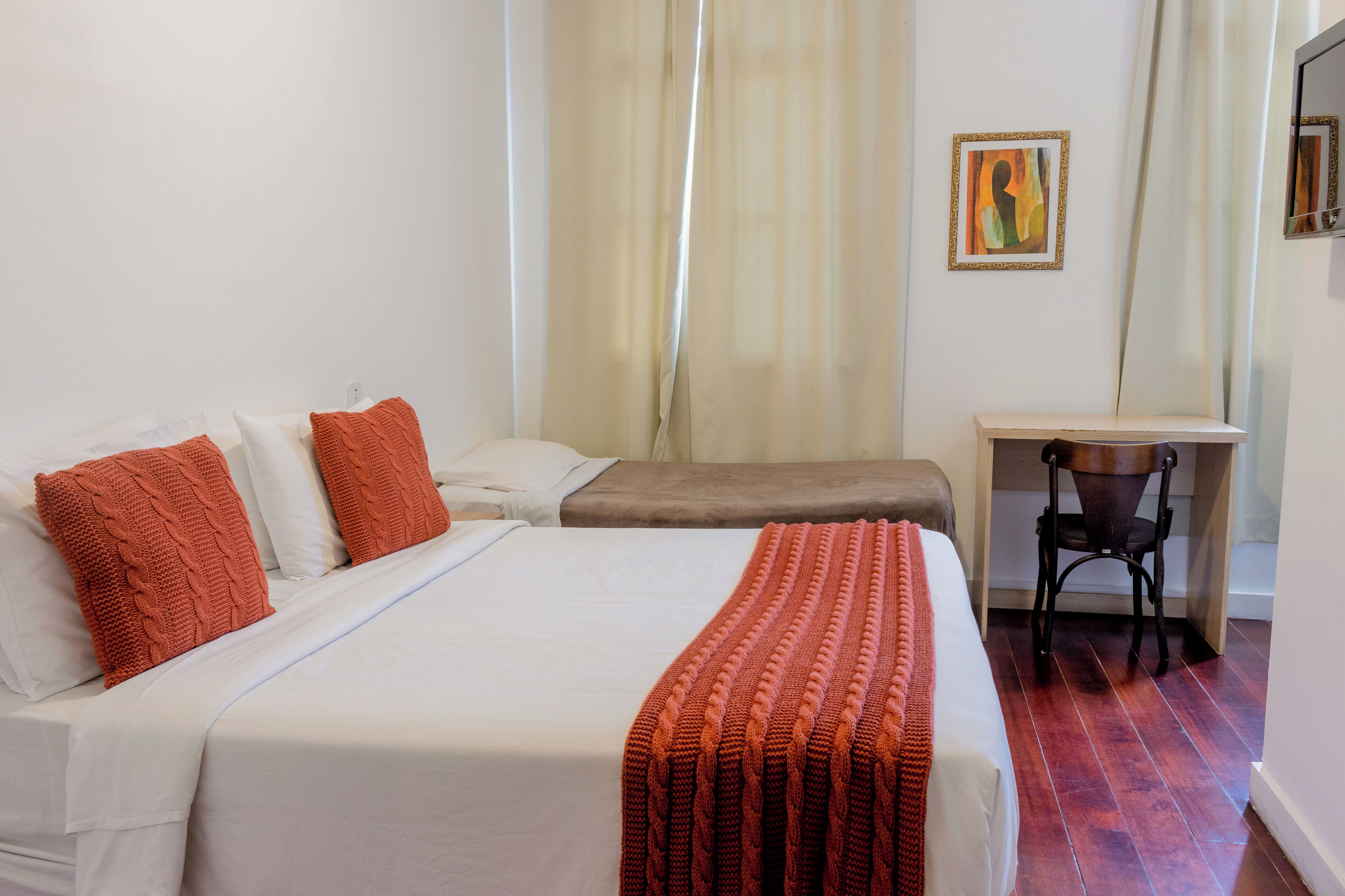 A hotel room with two beds, a desk, and a chair.