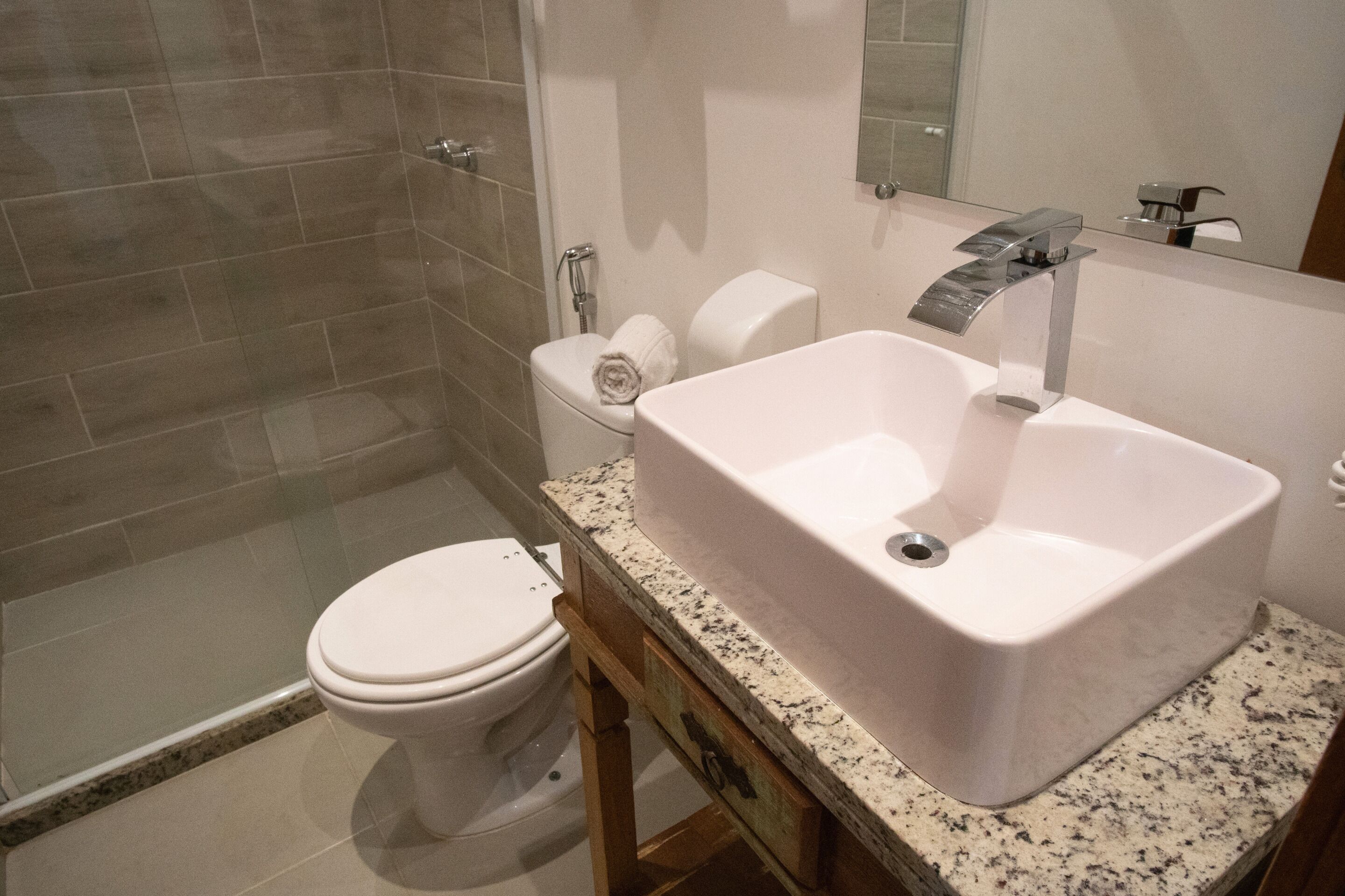 A modern bathroom with a white sink, a toilet, and a shower area.