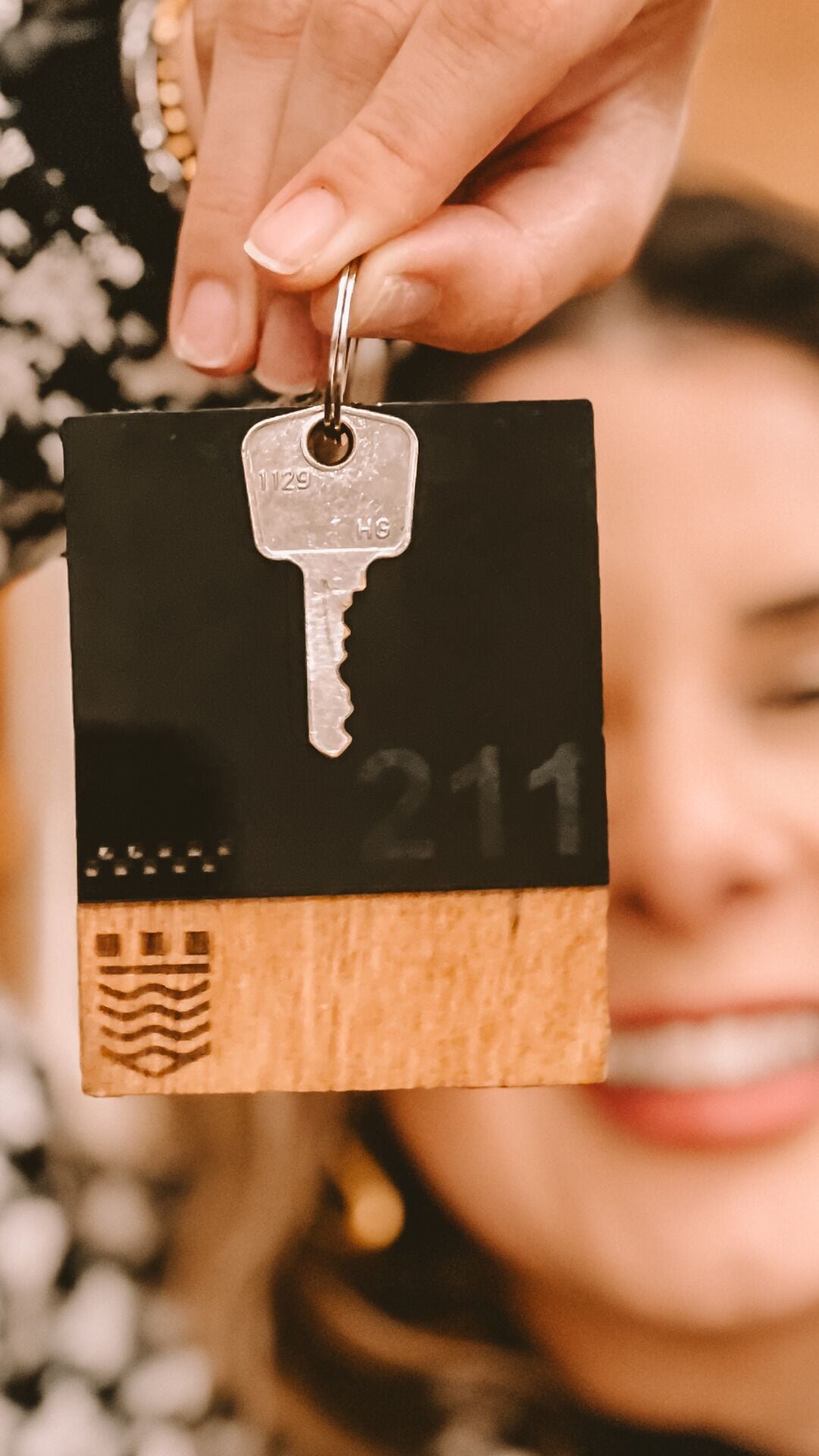 A hand holding a key with a tag that has the number 211 on it.
