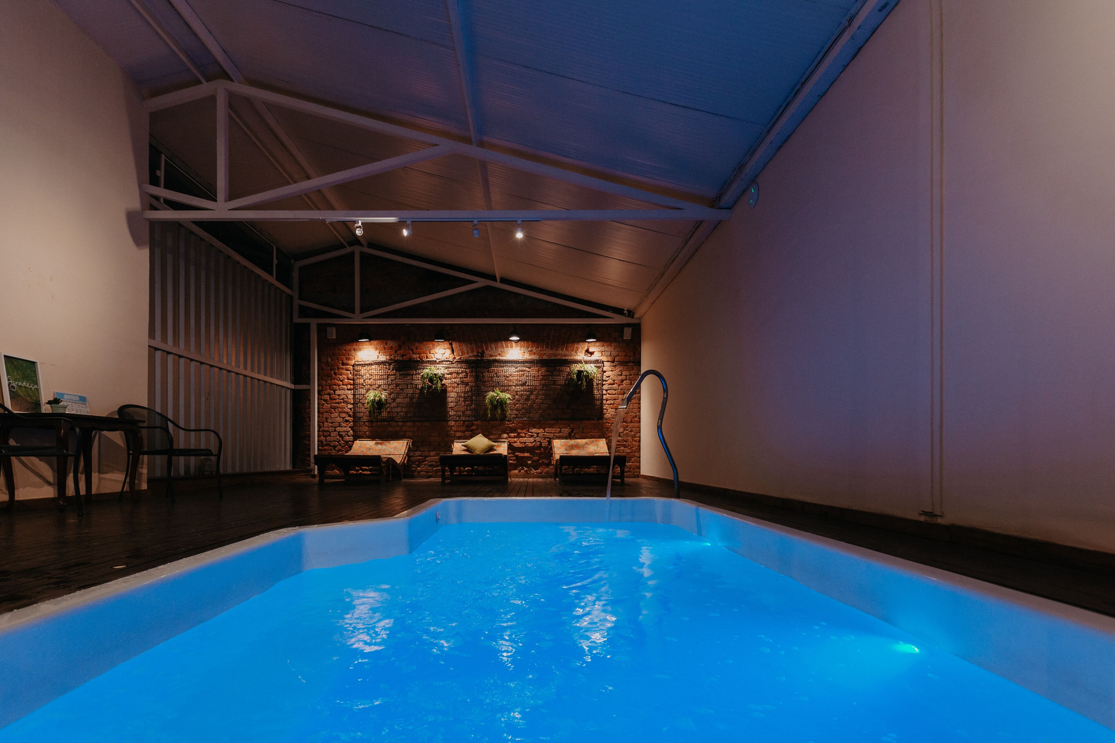 An indoor swimming pool with a brick wall and seating area.