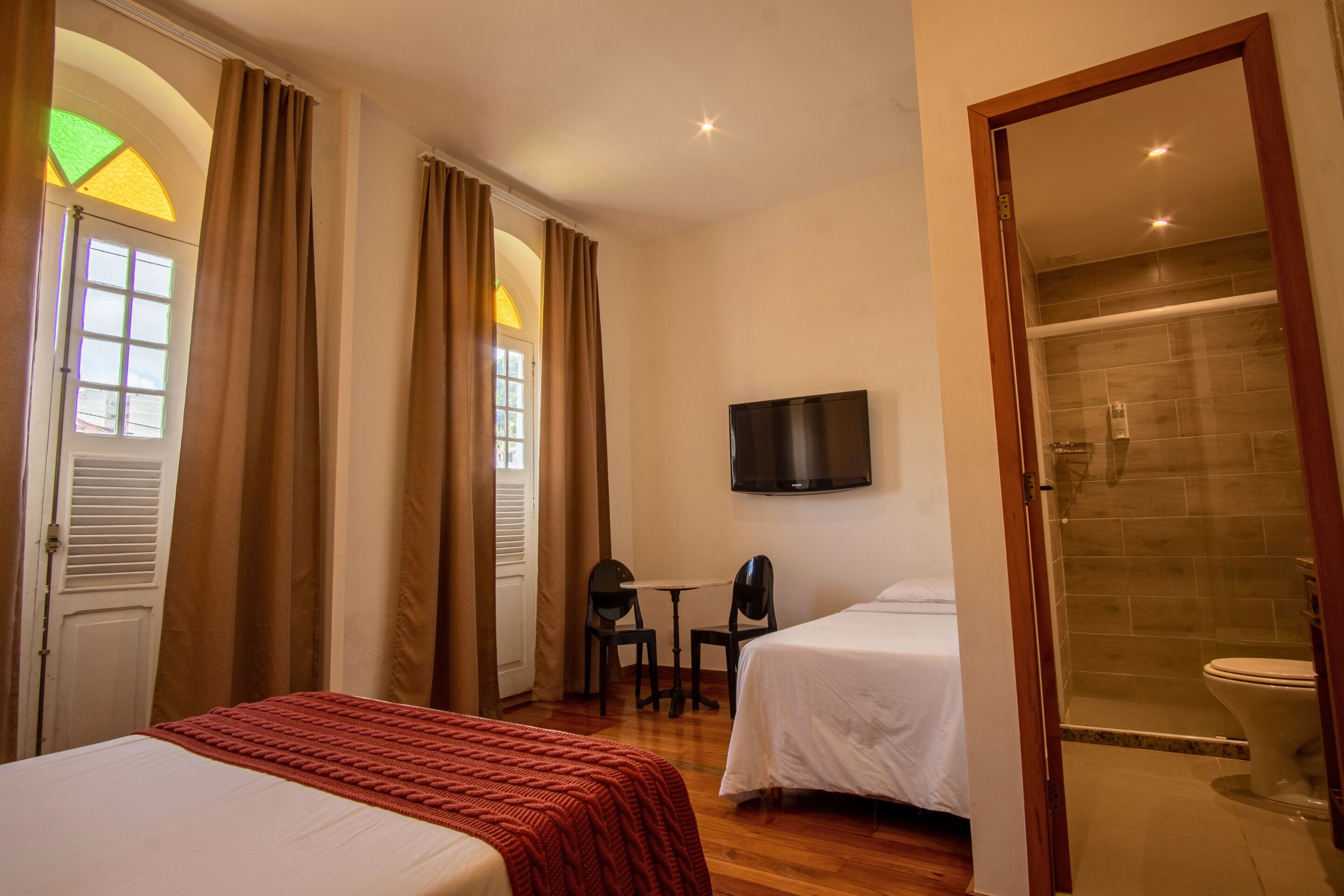 Een hotelkamer met twee bedden, een televisie, een klein tafeltje met stoelen en een douche.