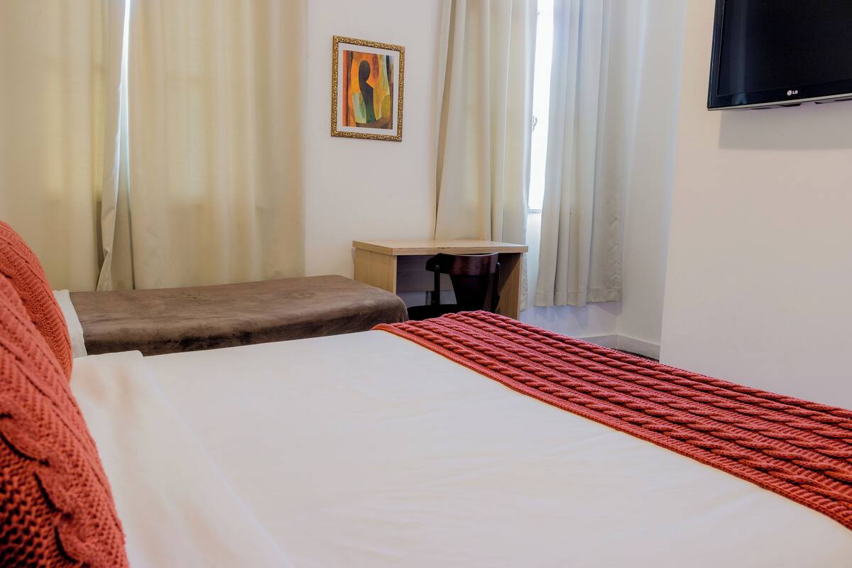 A hotel room with a bed, a desk, and a TV.