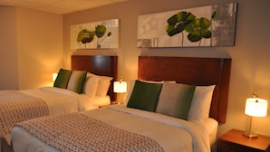 A hotel room with two beds, each with a wooden headboard, white bedding, and green pillows. There are two wall-mounted lamps on wooden nightstands. - Auberge du Marchand (Maria)