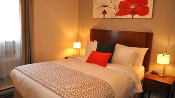 Habitación de hotel con una cama grande, dos lámparas de noche, una ventana con cortinas y una obra de arte floral en la pared.