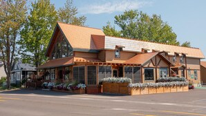 A two-story building with a sloped roof, large windows, and wooden exterior. - Auberge du Marchand (Maria)
