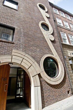 A building with a distinctive curved architectural feature and a circular window. - Native Monument (London)