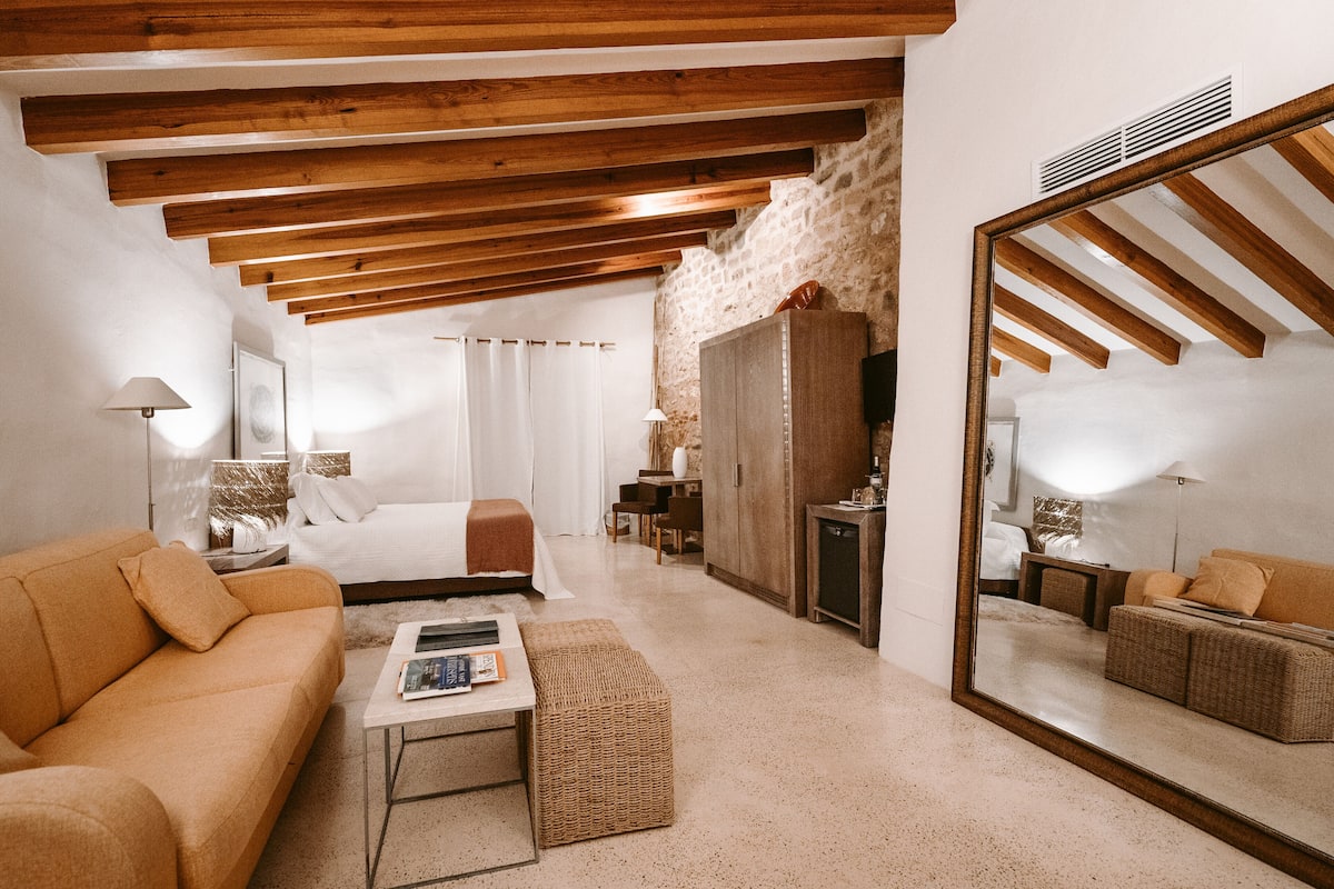Una habitaci ón amplia con una cama grande, un sofá, una mesita y un espejo.