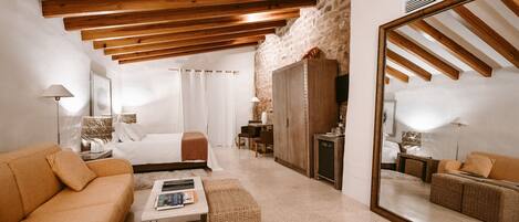 A spacious room with a large bed, a sofa, a small table, and a mirror.