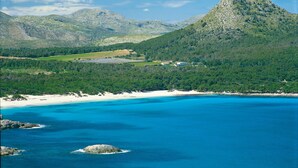 Eine Küstenlandschaft mit einem Berg, Strand und klarem, blauem Wasser.