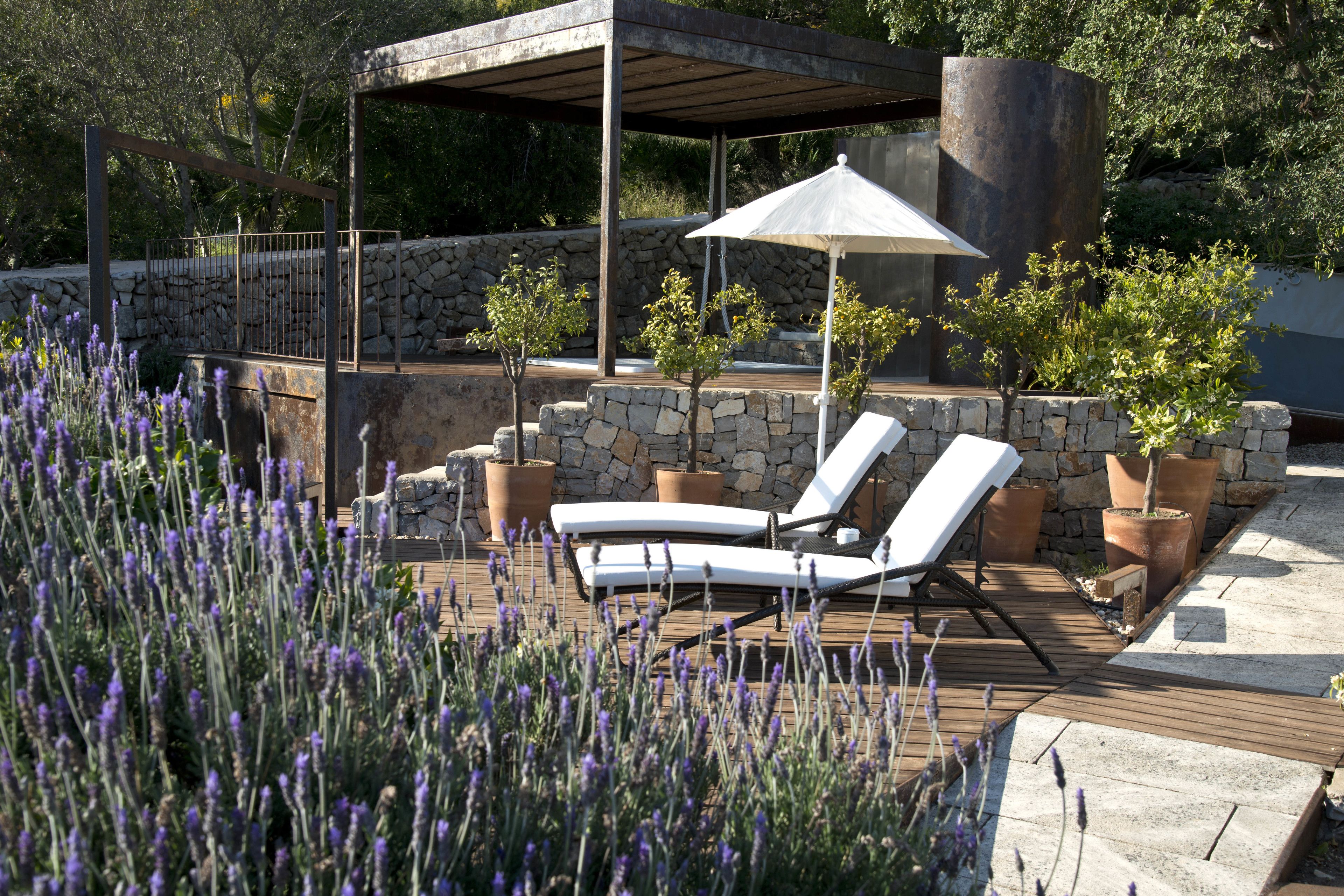 A wooden deck with two lounge chairs and a pergola with an umbrella.