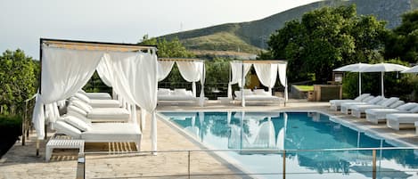 Una piscina al aire libre, sombrillas, tumbonas