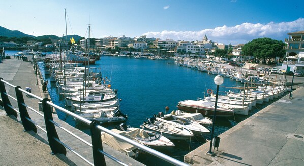 A marina with numerous boats docked, a clear sky, and buildings in the background.