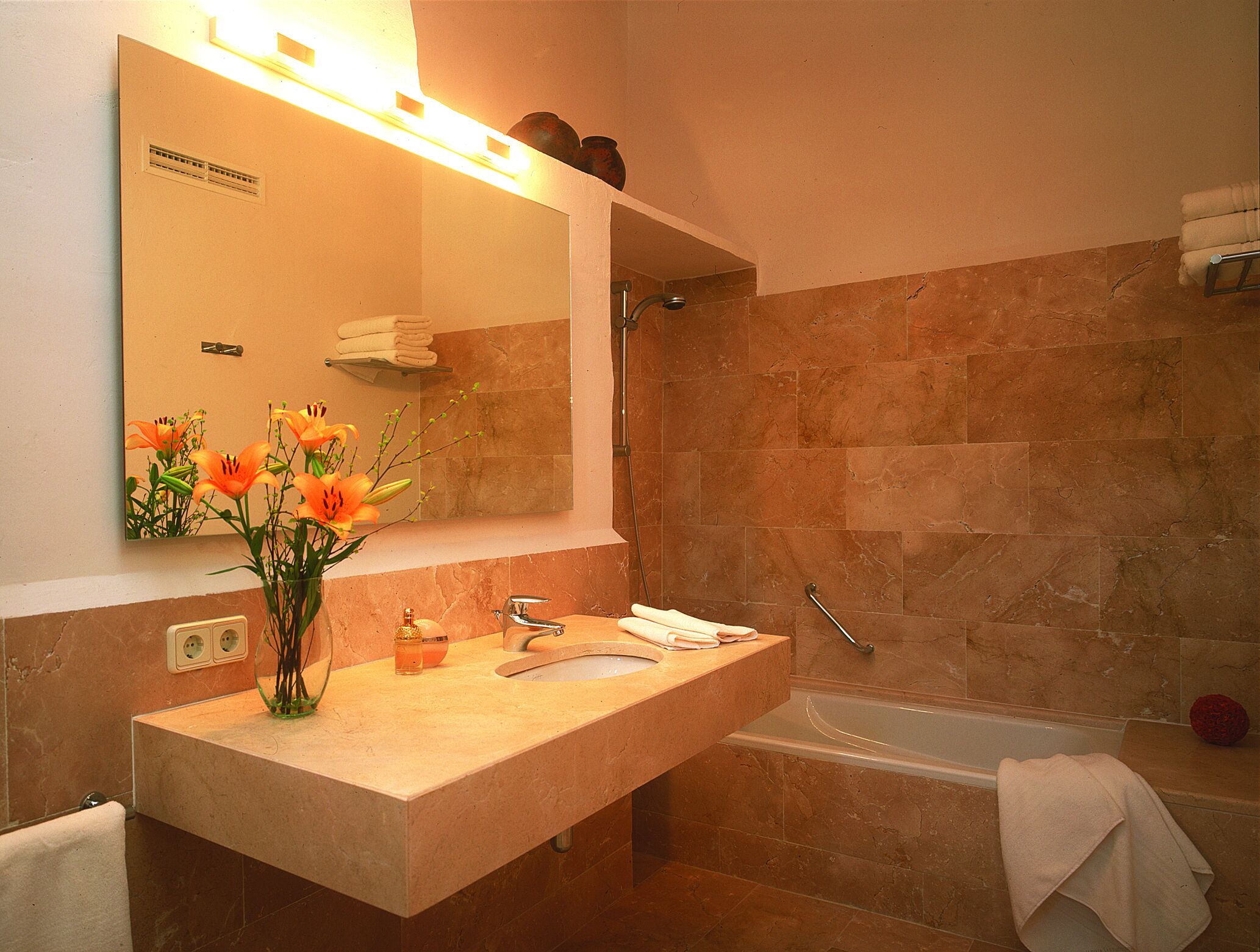 A bathroom with a sink, mirror, and bathtub.